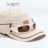 Front side view of cream nylon sun cap with neck flap, rust-red tree logo, zip pocket, piped brim and sunglasses slits,. Urban Monkey®