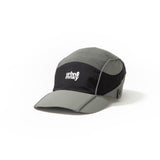 Side view of olive-grey and black color-block nylon cap with white stacked logo and pine tree icon. Urban Monkey®