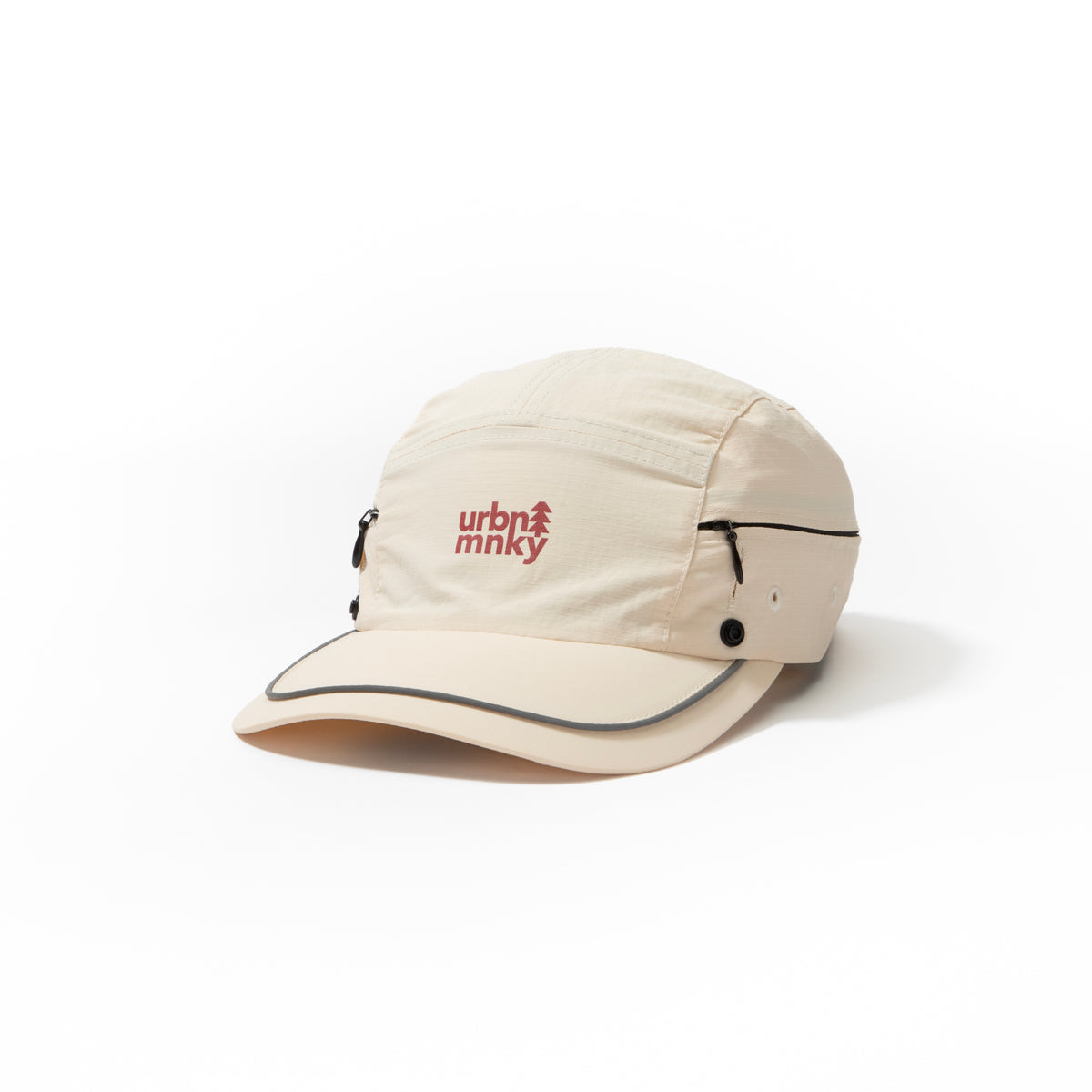 Front side view of cream nylon sun cap with rust-red embroidered logo, zip pocket, and snap button. Urban Monkey®