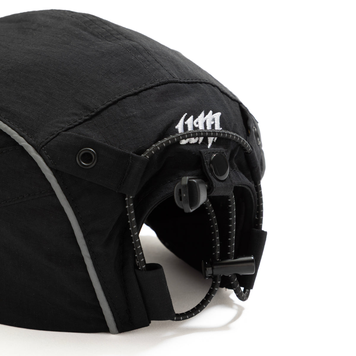 Back view of black ripstop nylon cap with grey piping, with white embroidered logo and adjustable strap Urban Monkey®