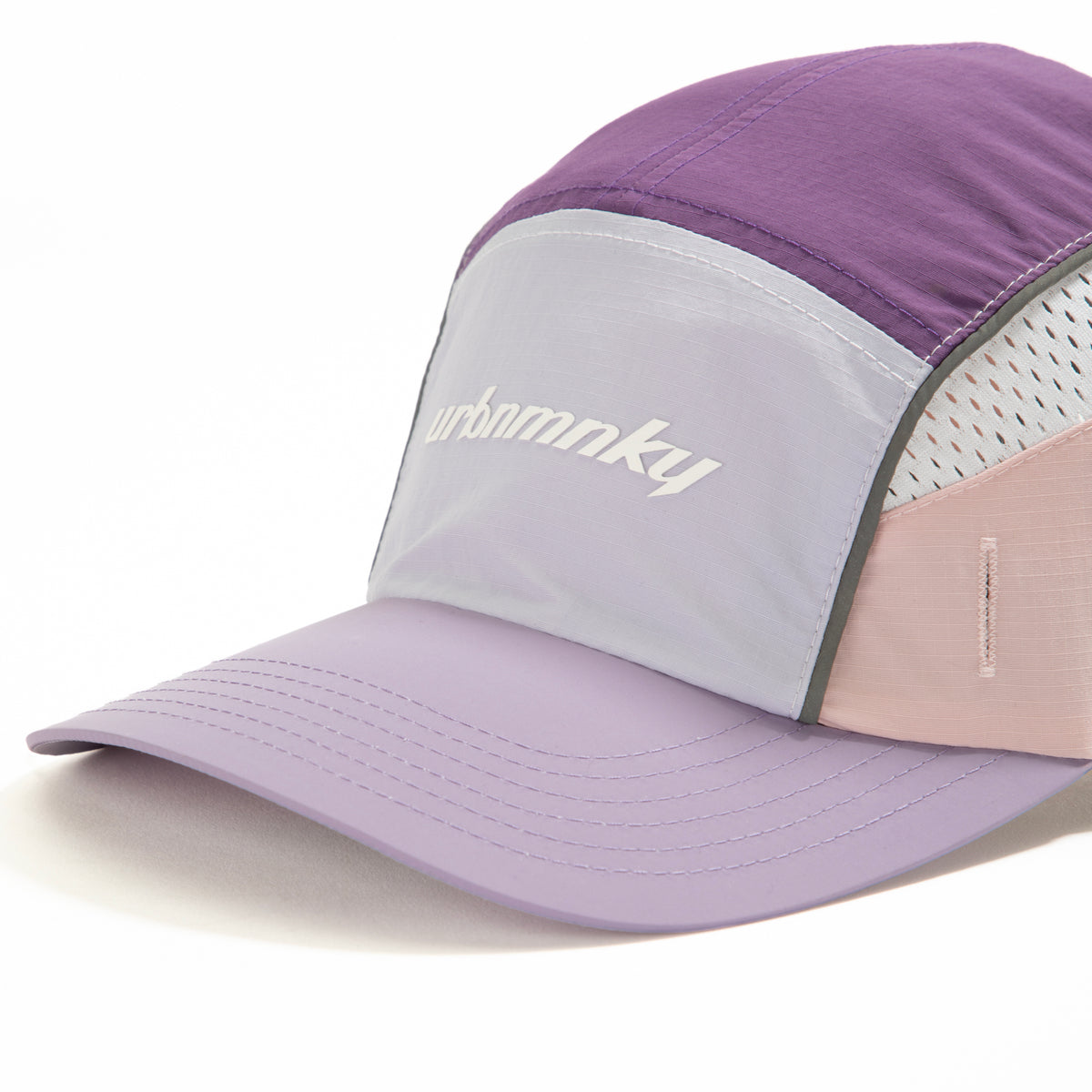 Side view of lilac, purple and pink color-block nylon cap with white logo, grey piping and sunglasses slits. Urban Monkey®