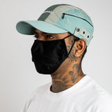 Side view Sage green, grey and mint color-block nylon cap with white embroidered logo, side zip pockets and metal side clips.” Urban Monkey®